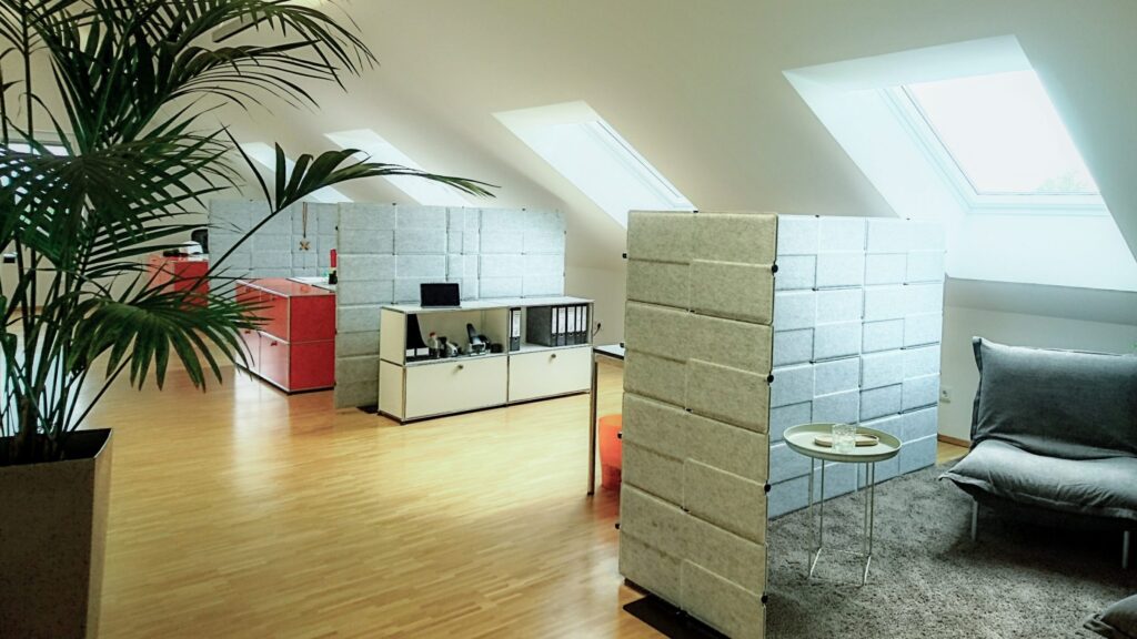 Ein Büroraum mit Betonartigen Trennwänden und hellem Laminat.